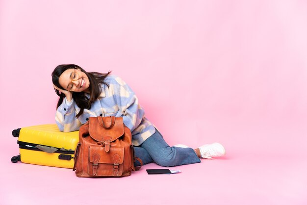 Reiziger vrouw met een koffer zittend op de vloer lachen