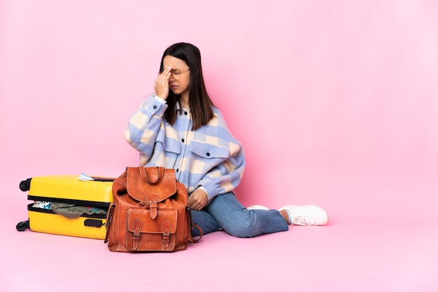 Reiziger vrouw met een koffer zittend op de vloer met hoofdpijn