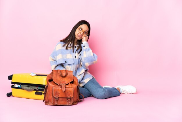 Reiziger vrouw met een koffer zittend op de vloer met vermoeide en verveelde uitdrukking