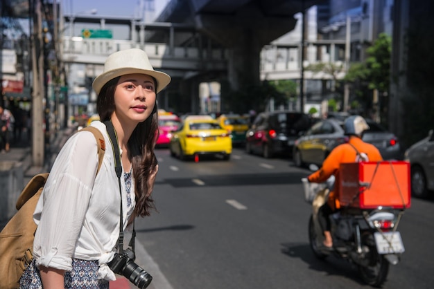 Reiziger vrouw op de weg op zoek naar taxi achtergrond is stedelijke verkeersopstopping. Aziatische vrouw met het bellen van een taxi op de straat van Bangkok, Thailand.