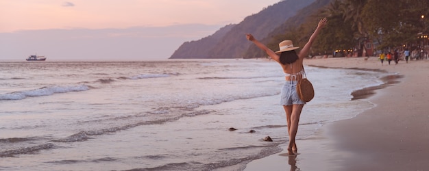 Reizigers Aziatische vrouw met hoed ontspannen en sightseeing op het strand bij zonsondergang in Koh Chang, Trat, Thailand