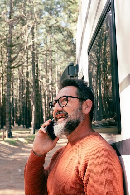 Reizigers man die buiten een moderne camper van staat en geniet van een bestemming in de natuur bos bossen Mensen en voertuigen reizen rv levensstijl Vanlife Alternatief huis en vakantie vakantie mensen