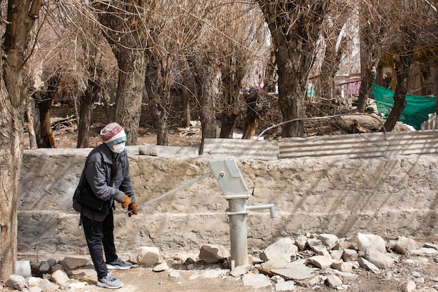 Reizigers thaise vrouwen testen gebruik antieke grondwaterput handmatige hefboompomp buiten in het steegje van het dorp Ladakh in de Himalaya-vallei in Jammu en Kasjmir, India tijdens het winterseizoen