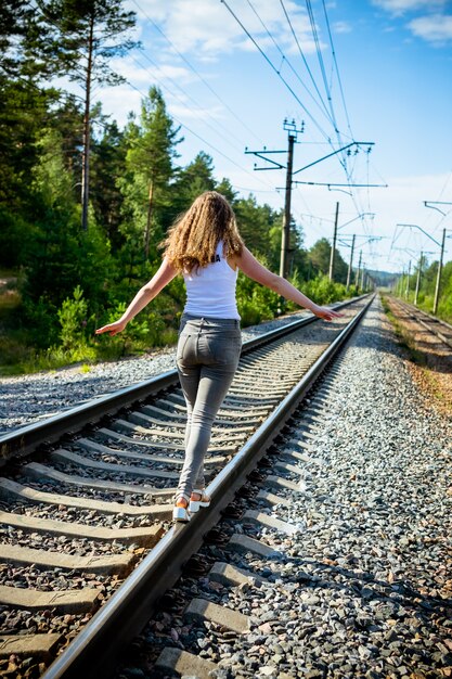 Foto reizigersmeisje die in vrijetijdskleding langs de spoorweg naar de bestemming lopen.