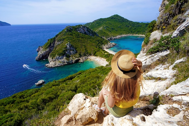 Reizigersmeisje die van landschap van Porto Timoni-gezichtspunt in Corfu, Griekenland genieten