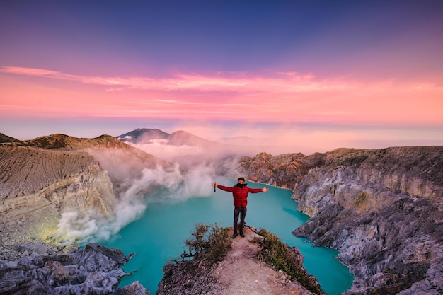 Reizigersmens die zich op de krater van Kawah Ijen-vulkaan bevindt met zonsopganghemel in de ochtend