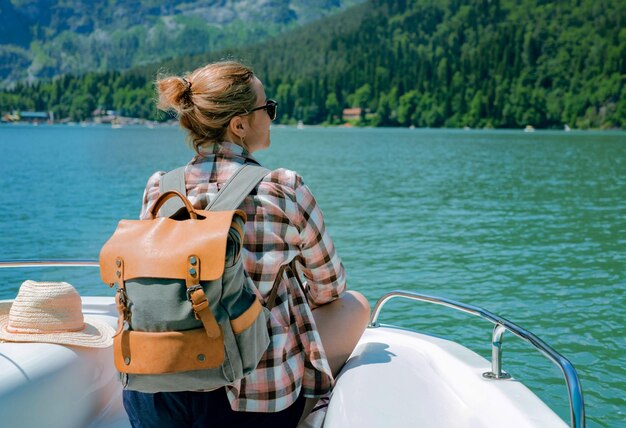 reizigersvrouw die geniet van een prachtig uitzicht op het turquoise meer en de bergen, zittend op een zeilboot