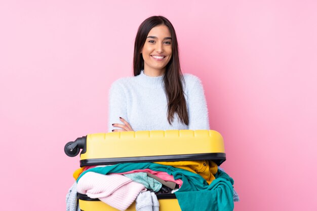 Reizigersvrouw met een koffer vol kleren over roze lachen