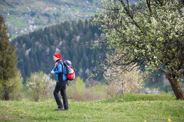 Reizigersvrouw met een rugzak dichtbij bloeiende boom