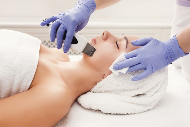 Rejuvenating facial treatment. Model getting lifting therapy massage in a beauty SPA salon. Exfoliation, stimulation and hydratation. Aesthetic cosmetology, closeup, copy space