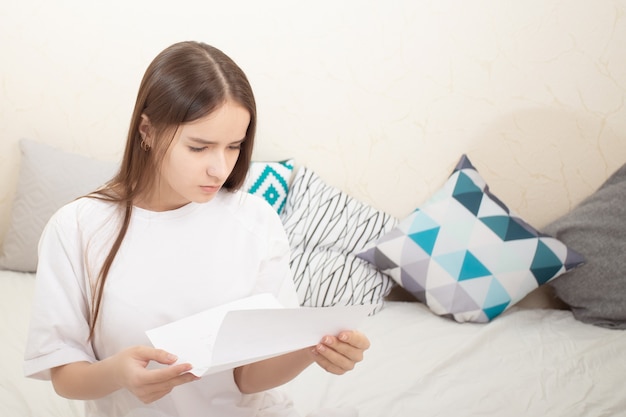 Rekening, bericht. Een meisje leest een betalingsbewijs, een brief thuis, kijkt aandachtig naar de tekst