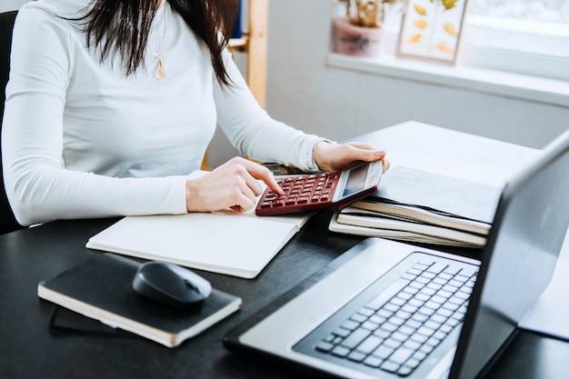 Rekeningsaldodefinitie vrouwelijke accountant die met laptop en rekenmachine op kantoor werkt