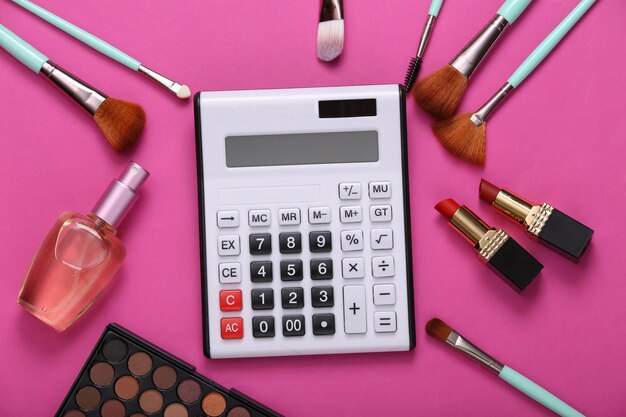 Rekenmachine en cosmetische accessoires op een roze achtergrond Cosmeticakosten
