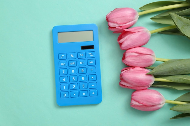 Rekenmachine en roze tulpen op blauwe achtergrond Romantisch schoonheid bedrijfsconcept