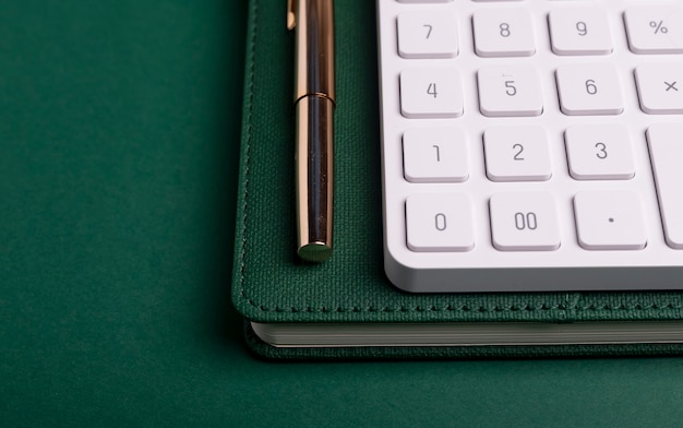 Rekenmachine op groene tafel en notitieboekje met pen. Werkplaats van accountant.