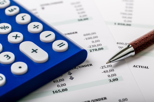 Foto rekenmachine, pen en het financieel verslag. detailopname