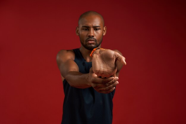Rekoefeningen portret van jonge en sterke Afro-Amerikaanse man in sportkleding die zich uitstrekt