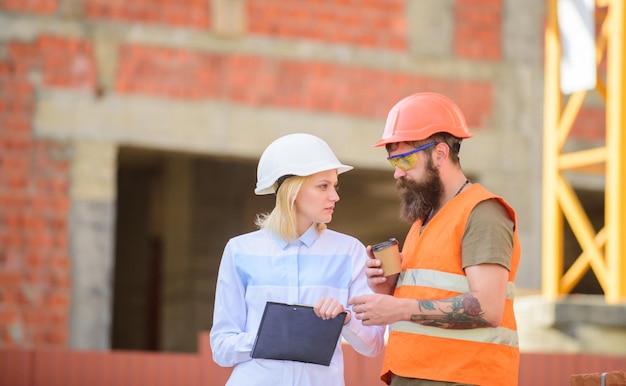 Relaties tussen bouwklanten en deelnemer bouwsector Bespreek voortgangsplan Vrouwelijke ingenieur en bouwer communiceren bouwplaats Bouwteam communicatieconcept