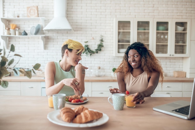 Photo relationship. couple of young adult happy girlfriends sitting having fun talking while having breakfast at home