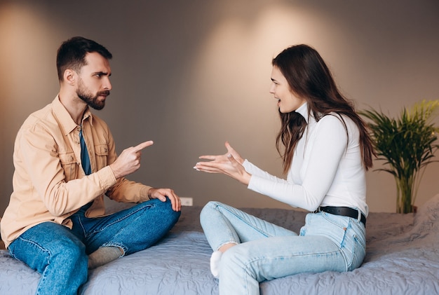 Relationship difficulties conflict and people concept unhappy\
couple having argument at home young couple with problems almost\
fight while sitting at sofa