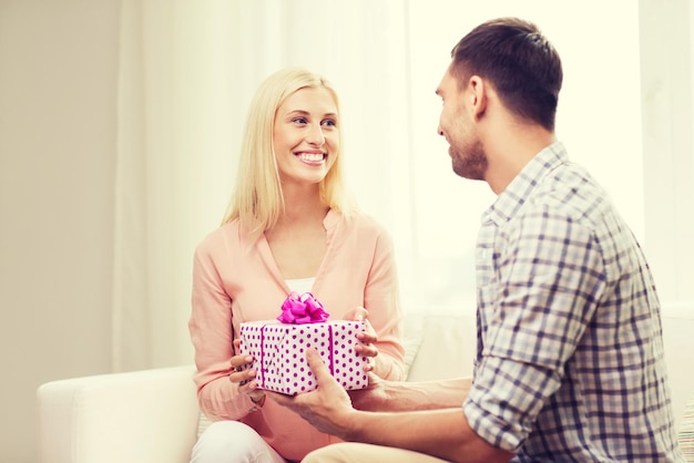 relationships, love, people, birthday and holidays concept - happy man giving woman gift box at home