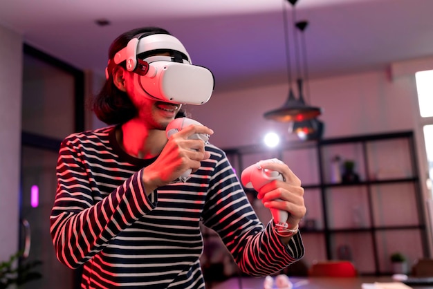 Photo relax asian adult man wearing virtual reality headset and holding controllers plays in a boxing sport video game at home playing vr active sport game online in the living room with rgb lighting mood
