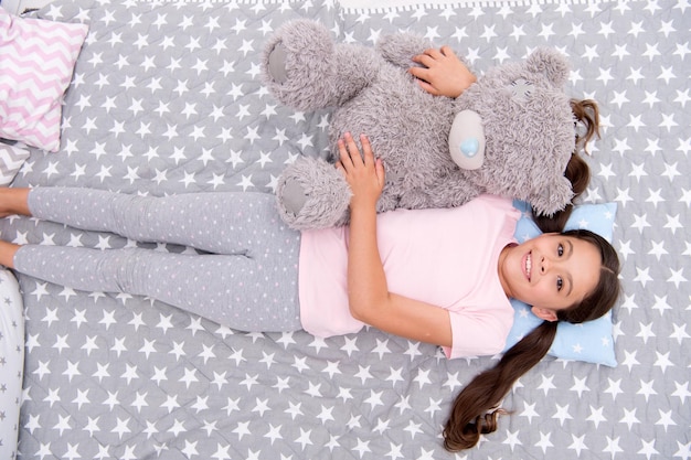 Relax concept Little girl relax in bed Cute child relax with teddy bear toy Relax and enjoy life