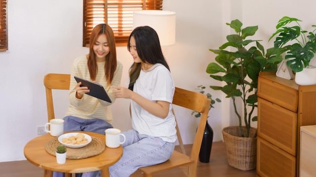 Relax at home concept lgbt lesbian couple pointing and looking\
on tablet while working together