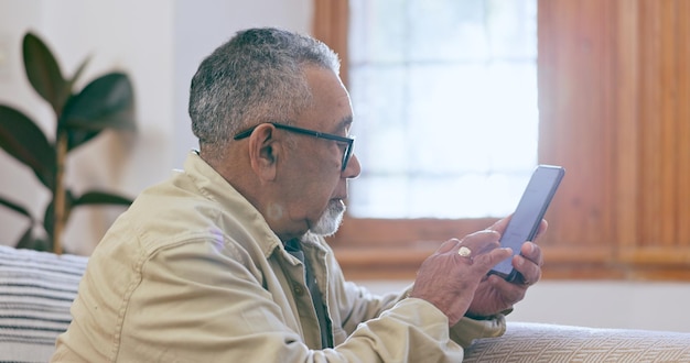 Photo relax home and senior man with a smartphone internet and connection with social media in a lounge mature person elderly guy and pensioner with a cellphone digital app and communication with text