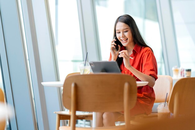 Rilassati per il tempo libero attraente imprenditore freelance asiatico femminile sorridente e divertiti a lavorare con smartphone e laptop al bar con il concetto di idee casual nomadi digitali di affari della città sfocata