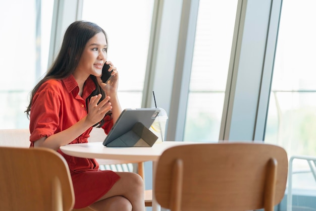 Photo relax leisure attractive smart asian female freelance entrepreneur smile and enjoy working with smartphone and laptop at cafe with blur city business digital nomad casual ideas concept