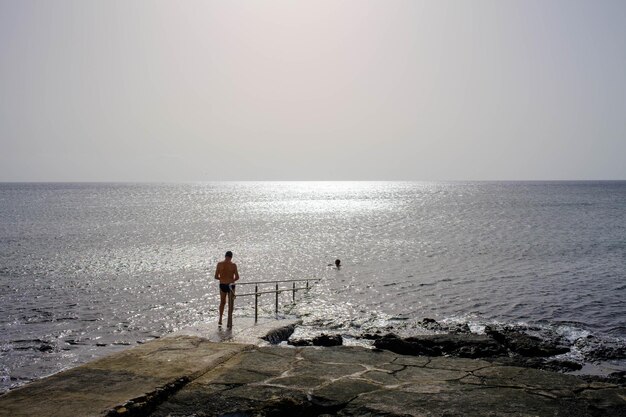 Photo relax in search of freedom. man on the pier with the silver sea