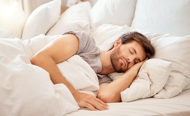 Rilassa il sonno e la pace di un uomo stanco che dorme in una camera da letto a casa sognare rilassarsi e riposare calma persona attraente con gli occhi chiusi su un cuscino a casa sua al mattino facendo un pisolino