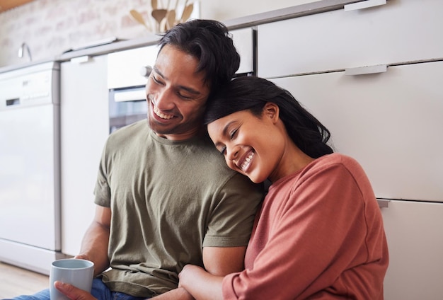 Relax smile and couple with coffee in the morning on the floor of kitchen in their house Happy and young man and woman with love marriage and happiness in their home with tea for calm and peace