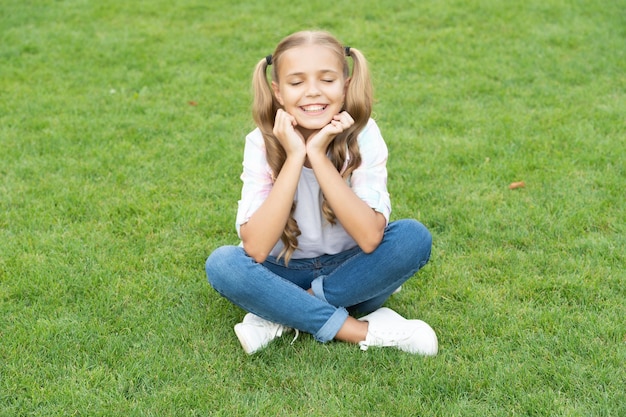 夏の芝生でリラックスする女の子 草の上で静かにリラックスする 十代の少女の幸せな子供時代 夏は公園でリラックスする 屋外に座っている十代の少女 畏敬の念を感じる十代の子供時代のライフスタイル