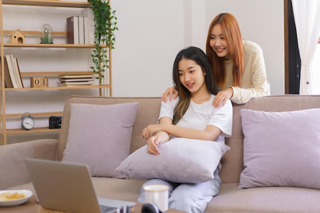 Relaxation concept Lesbian female sits on couch with girlfriend stand behind her to watching movie