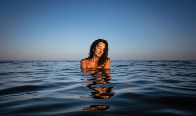 Relaxation and healthy lifestyle. Young beautiful and emotional woman swims in the sea on a sunny day. Portrait in sea water