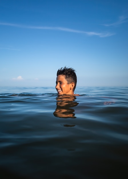 Relaxation and healthy lifestyle. Young boy teenager bathes in the sea.