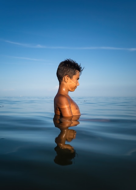 Relaxation and healthy lifestyle. Young boy teenager bathes in the sea.