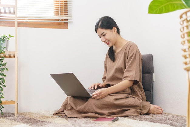 Relaxation lifestyle concept Young Asian woman use laptop for entertainment in living room at home