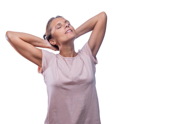 A relaxed adult woman standing with her hands behind head