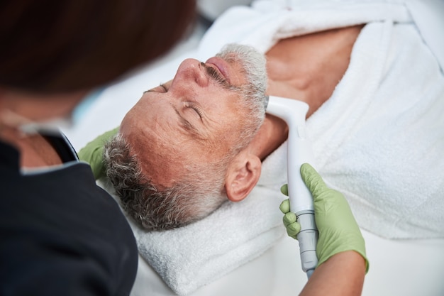 a relaxed aging man laying on a spa table during photofacial procedure