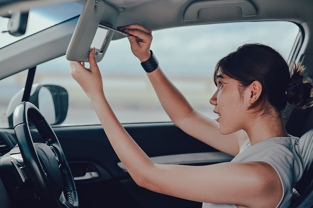 鏡で見ているリラックスしたasisn女性。車の上に座っています。ライフスタイルと人々の概念。