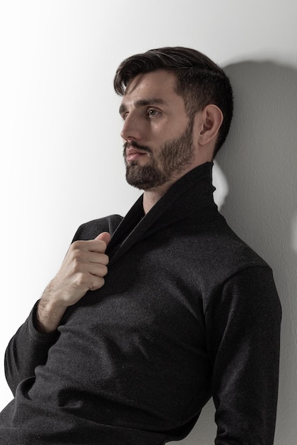 Relaxed bearded man leaning on the white wall