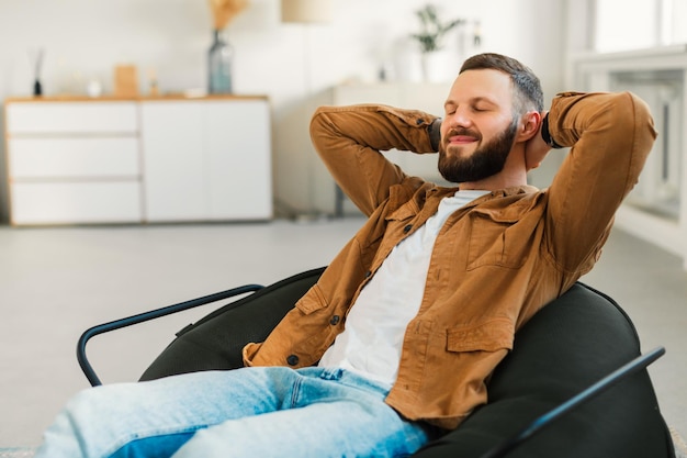 Photo relaxed bearded man resting with eyes closed sitting at home