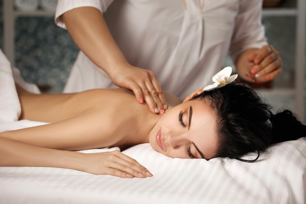 Photo relaxed beautiful young woman receiving massage in spa salon. beauty treatment