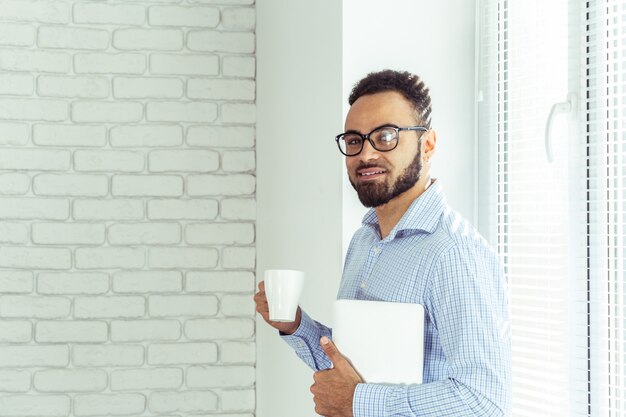 Photo relaxed black businessman in office, drink coffee