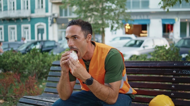 Relaxed builder resting break eating lunch street closeup man tasting sandwich