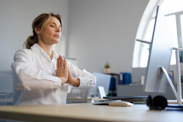 Foto donna d'affari rilassata meditando seduto al computer in ufficio