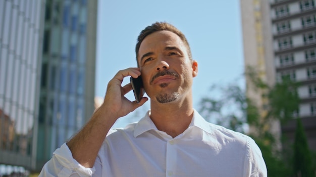 Relaxed businessman calling cellphone sunbeams street closeup happy man walking